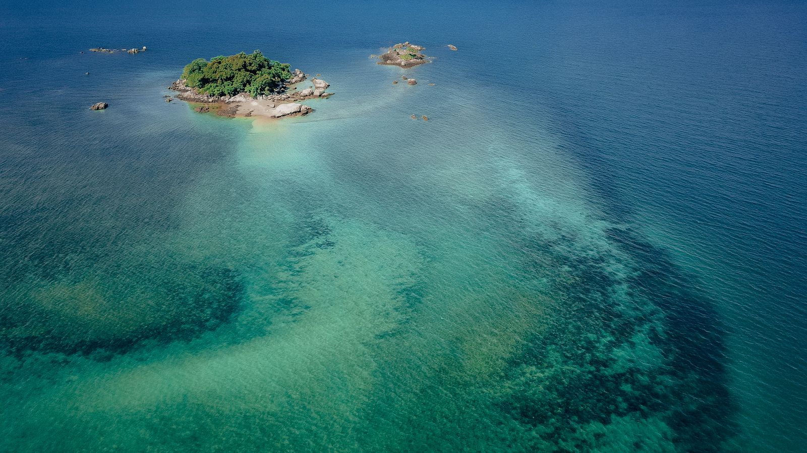 A small green island in clear tropical water.