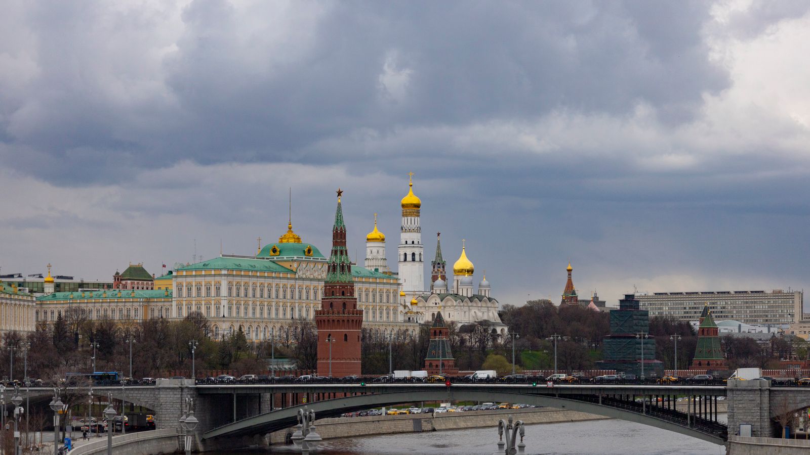 The Moscow Kremlin and a river bridge under cloudy skies.