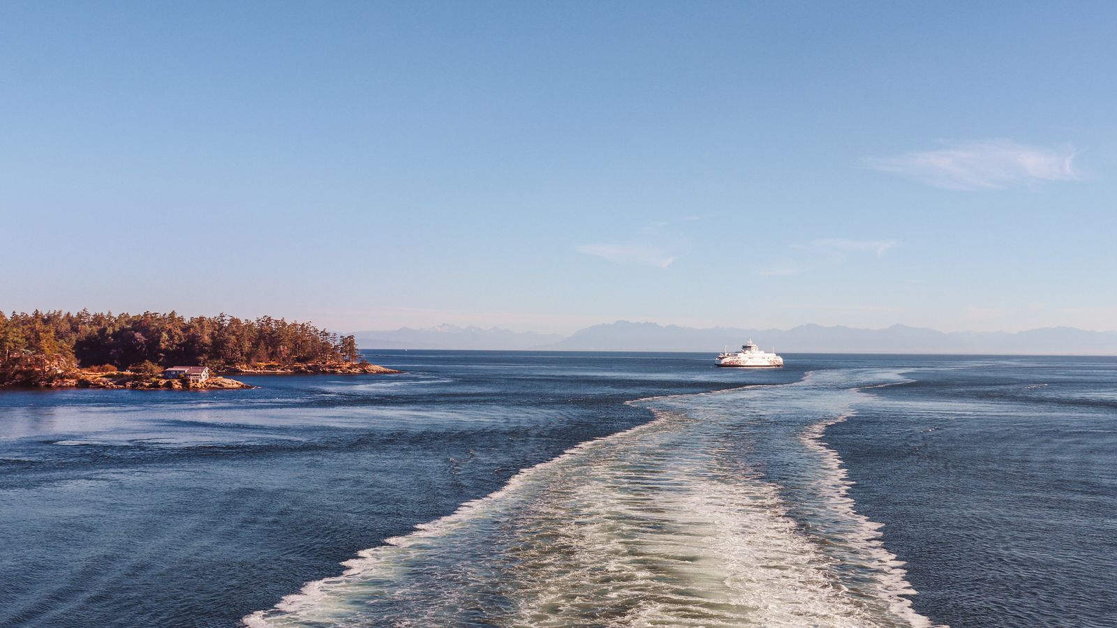 A ferry crossing calm water beside a wooded island near Victoria, British Columbia.