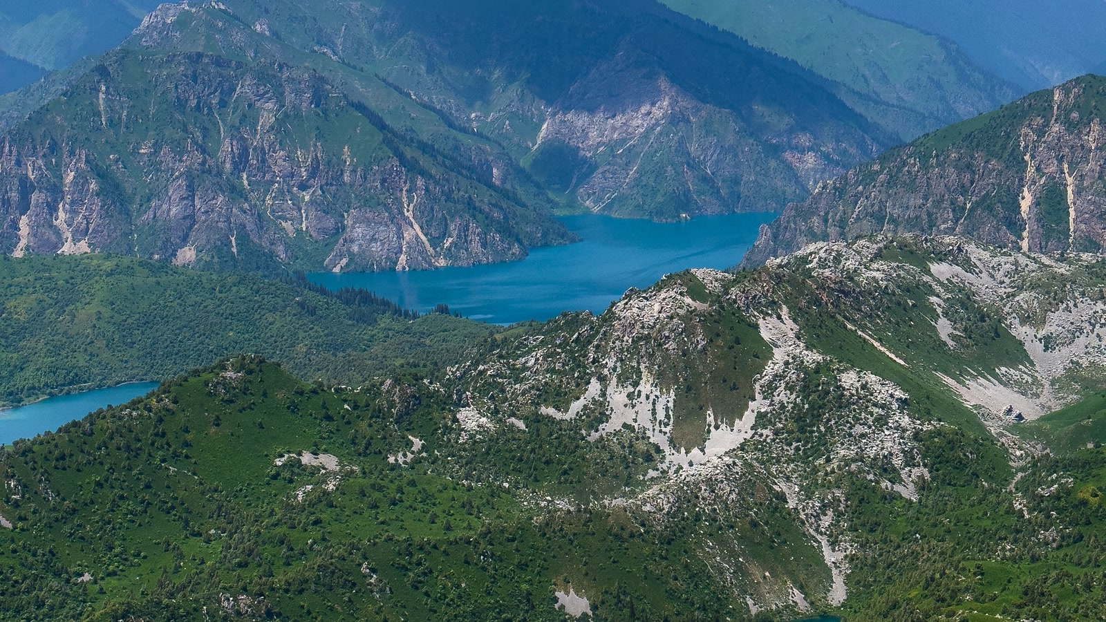 A turquoise alpine lake winds through rugged high mountains in western Kyrgyzstan.