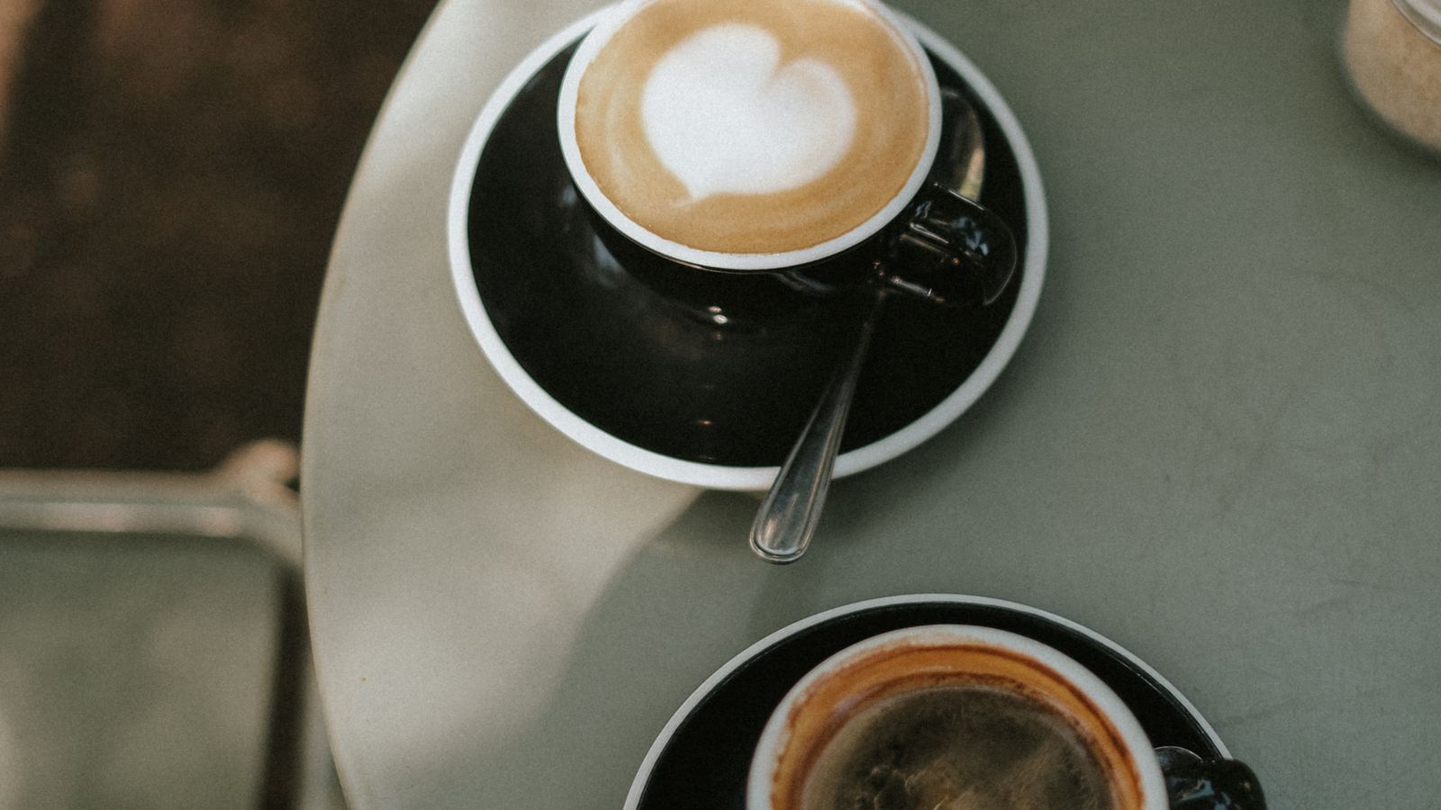 Two coffee cups on saucers seen from above on a pale table