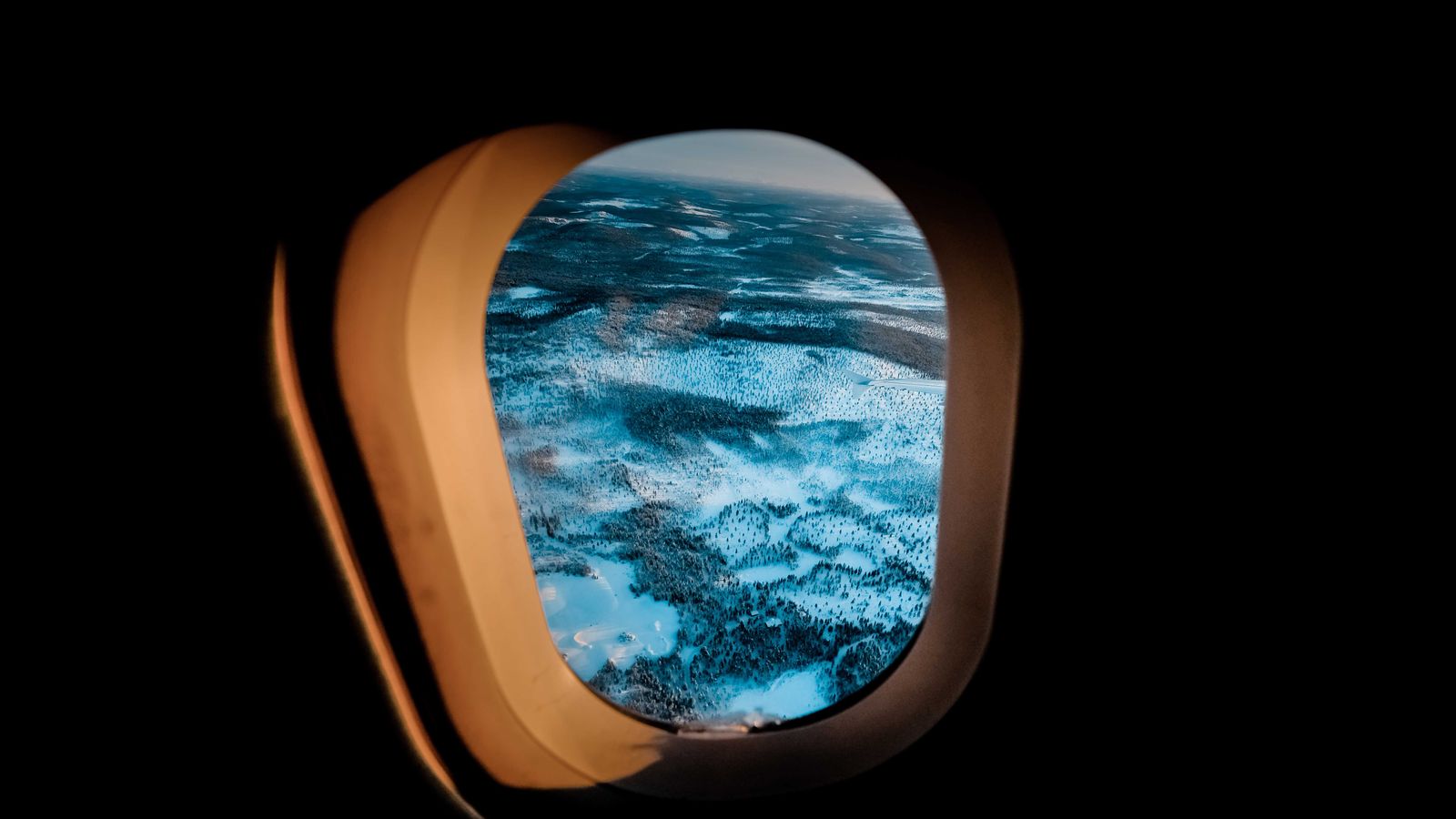Snowy landscape viewed through an airplane window