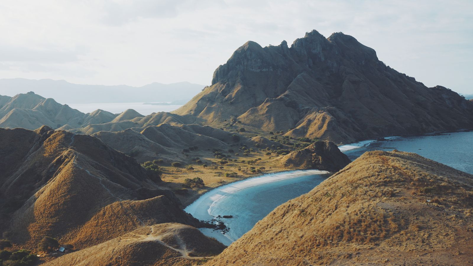 Rugged hills and a turquoise bay on Padar Island in Komodo National Park, Indonesia.