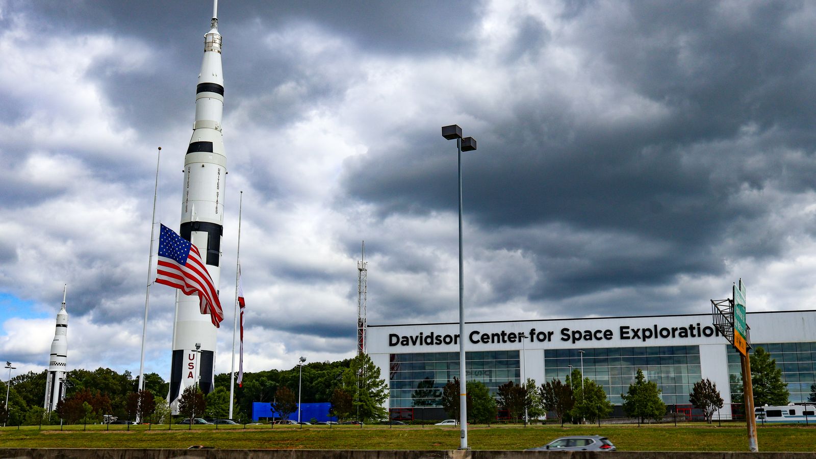 Outdoor rocket display beside a long white museum building under cloudy sky