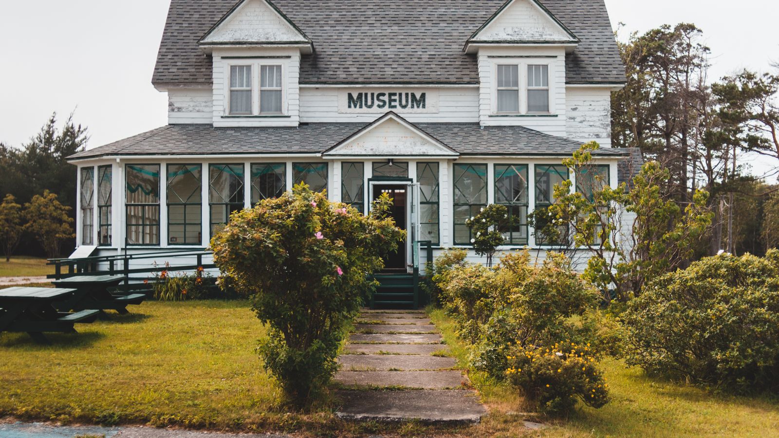 Small wooden house marked Museum with a walkway and green lawn