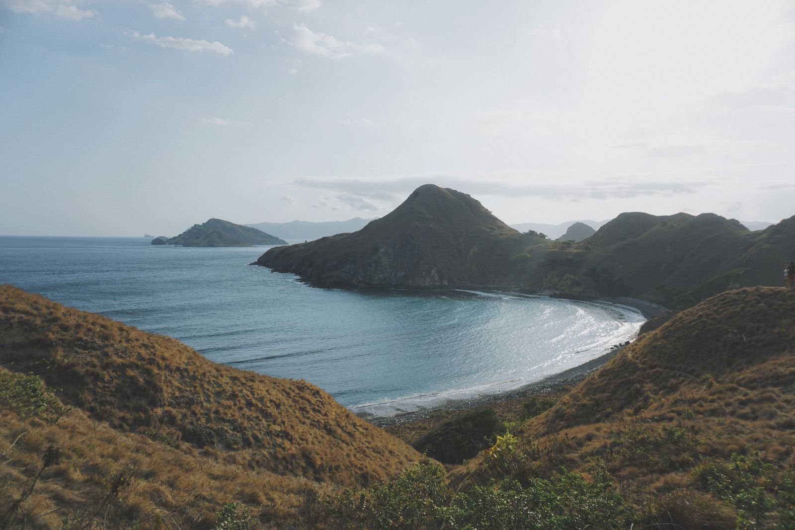 Grassy hills and a curved bay below the Padar Island viewpoint in Komodo National Park, Indonesia